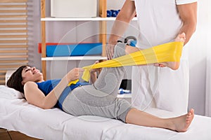 Physiotherapist Giving Leg Treatment With Exercise Band