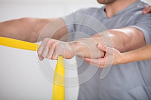 Physiotherapist Giving Man A Training With Exercise Band