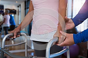 Physiotherapist helping patient to walk with walking frame