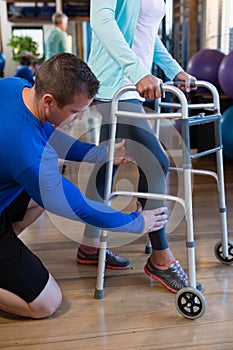 Physiotherapist helping patient to walk with walking frame