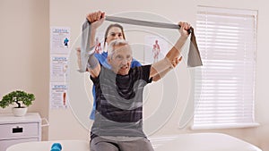 Physiotherapist helping senior man exercise with fit band