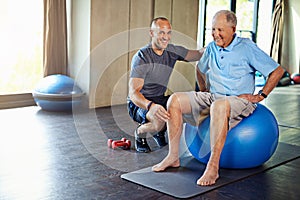 Physiotherapist, helping and senior man with yoga ball, training and elderly support for care. Men, gym and exercise for
