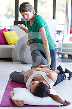 Physiotherapist helping to beautiful pregnant woman for doing pilates exercises preparing for childbirth