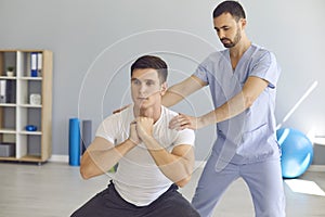 Physiotherapist helping young athlete do squats during rehabilitation therapy after sports injury