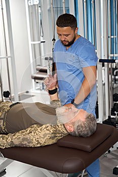 Physiotherapist helps a patient perform exercises to stretch arm muscles