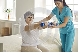 Physiotherapist or home care nurse helping senior woman do rehabilitation exercise