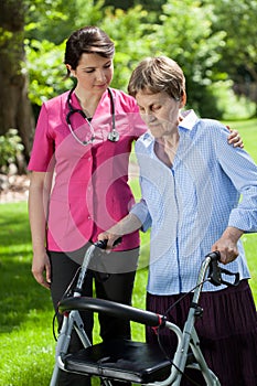 Physiotherapist looking at woman using orthopedic walker