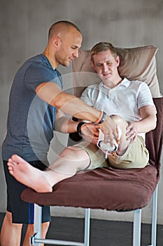 Physiotherapist, man with disability as fitness, recovery or teamwork in health, medical or wellness. Bed, people or leg