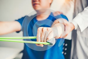 Physiotherapist man giving resistance band exercise treatment About Arm and Shoulder of athlete male patient Physical therapy