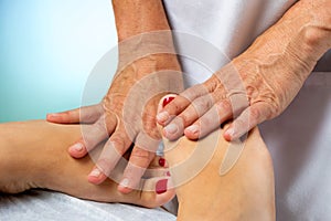 Physiotherapist manipulating female feet with hands.