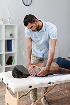 physiotherapist massaging shoulder of middle aged