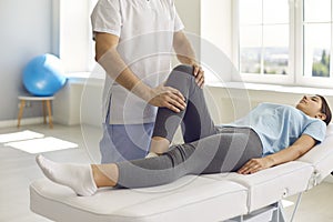 Physiotherapist in modern medical center working with young woman who has leg problem