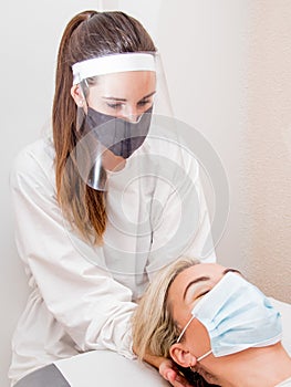 Female physiotherapist performing a massage with protections for the virus photo