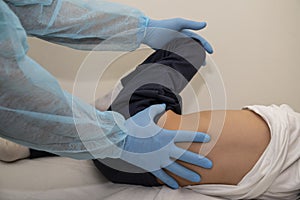 Physiotherapist performs rehabilitation therapy for the child lying on his side on the orthopedic bed.