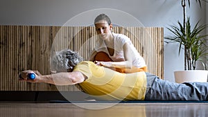 Physiotherapist or personal trainer working with a senior man helping him with his daily exercise routine