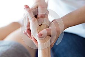 Physiotherapist pressing specific spots on female palm.