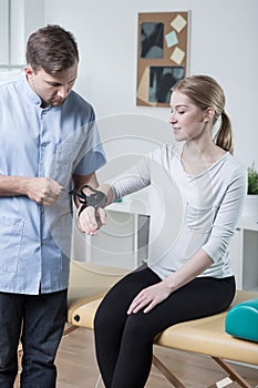 Physiotherapist putting orthosis on hand