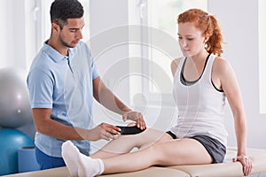 Physiotherapist putting tapes on patient`s leg during kinesiotaping photo