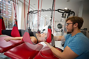 Physiotherapist-rehabilitator fixes a woman in a suspension loop system