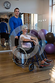 Physiotherapist with senior woman on wheelchair in clinic