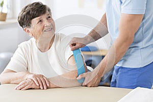 Physiotherapist sticking kinesiotape to woman