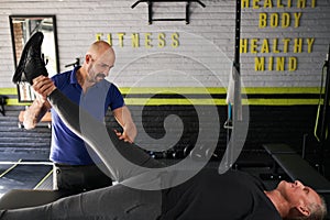 Physiotherapist stretching mature, elderly man, strength rehabilitation