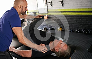 Physiotherapist stretching mature, elderly man, strength rehabilitation