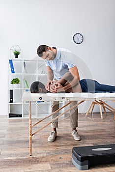 physiotherapist stretching shoulder of african american