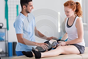 Physiotherapist supporting patient with stiffener on the leg photo