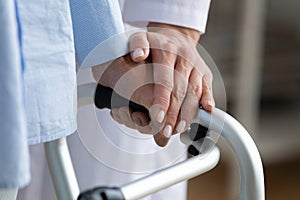 Physiotherapist touches woman hand while she holding walking frame closeup photo