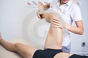 Physiotherapist working with woman giving her massage. Modern rehabilitation physiotherapy. Therapist treating injured legs of ath