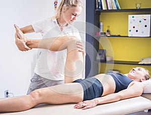 Physiotherapist working with woman giving her massage. Modern rehabilitation physiotherapy. Therapist treating injured legs of ath