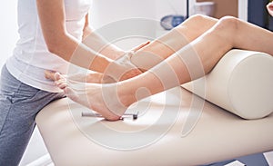 Physiotherapist working with woman giving her massage. Modern rehabilitation physiotherapy. Therapist treating injured legs of ath