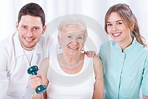 Physiotherapists and exercising elderly woman