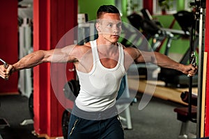 Physique fitness competitor works out in gym lifting dumbbells