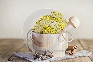 Phytotherapy, collecting medicinal herbs for tea and mixtures. Dried tansy flowers in a wooden mortar with pestle on a rustic