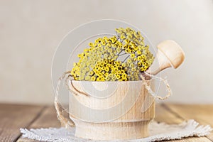 Phytotherapy, collecting medicinal useful herbs. Dried tansy flowers in a wooden mortar with pestle on a rustic background