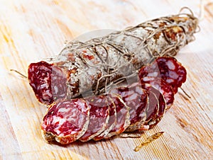 Piacenza salami cut in slices on a wooden surface, close-up