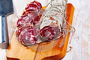 Piacenza salami cut in slices on a wooden surface, close-up