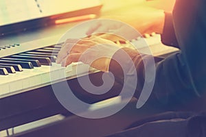 Pianist hands playing piano in a outdoor concert with sun flare photo