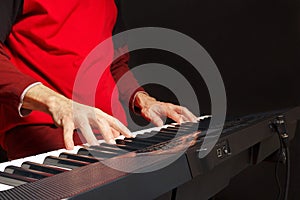 Pianist play the keys of the electronic piano on black background
