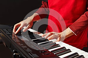 Pianist play the keys of the electronic synth on black background