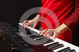 Pianist play the keys of the electronic synthesizer on black background