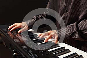 Pianist playing the electronic synthesizer on black background