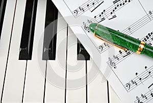 Piano keyboard with music score and pen