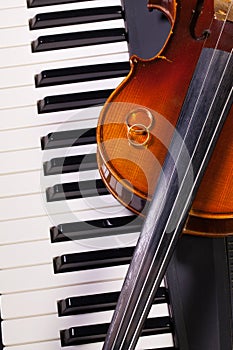 Piano keyboard, old violin and wedding rings