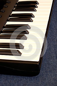 Piano keyboard with white and black keys on blue cotton background