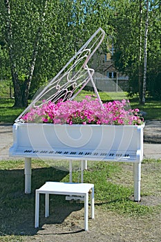 Piano with notes and petunia blossoming within. Keyboard musical instrument