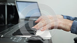 Piano player playing on midi piano keyboard at home music recording studio. Hands playing piano.