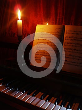 Piano and sheet music in the light of candle